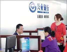  ??  ?? Left: An Industrial Bank employee introduces green financing products at a branch in Fuzhou, Fujian province.