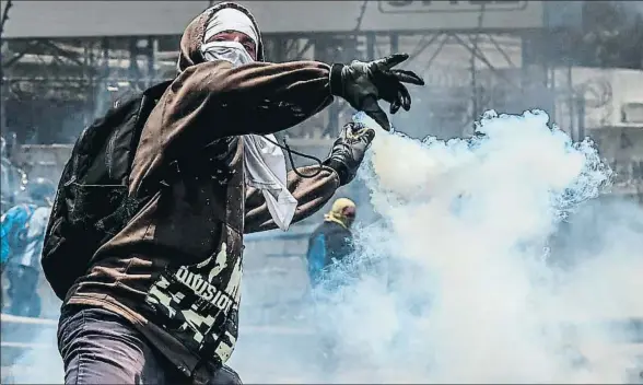  ?? JUAN BARRETO / AFP ?? Un manifestan­te se dispone a devolver a la policía una granada de gas durante las protestas en Caracas el lunes