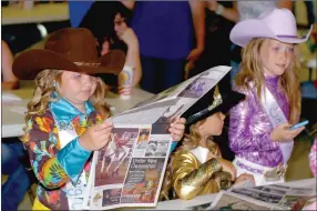 ?? MARK HUMPHREY ENTERPRISE-LEADER ?? Cowgirl features. In this photo from the 2015 Lincoln Rodeo, Kalleigh Jo Shreve, and her younger sister, Kenleigh Shreve, along with Savannah Perkins check out Enterprise-Leader news and photos from the annual special section devoted to coverage of the Lincoln Rodeo.
