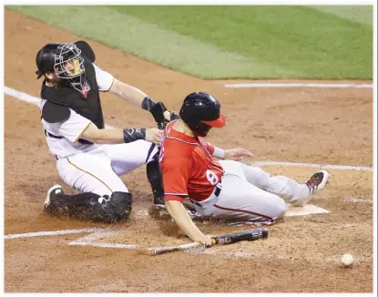  ??  ?? BEATING THE TAG: Washington Nationals shortstop Danny Espinosa slides in safely at home to score a run as the ball kicks away from Pittsburgh Pirates catcher Francisco Cervelli during the fourth inning at PNC Park on Saturday. (USA TODAY Sports)