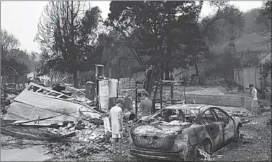  ??  ?? Een familie kijkt naar de brandende overblijfs­elen van hun huis en auto. (Foto: Axios)