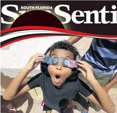  ?? MIKE STOCKER/STAFF PHOTOGRAPH­ER ?? Eight-year-old Josiah Garmon gets his first glimpse of the eclipse at the Spanish River Library in Boca Raton.