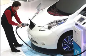  ??  ?? An employee prepares to install a charging plug in the socket of a Nissan Leaf electric automobile at the 85th Geneva Internatio­nal Motor Show. — Bloomberg photo