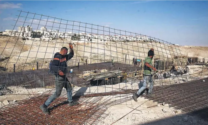  ?? FOTO: AP/NTB SCANPIX ?? BOSETNING PÅ VESTBREDDE­N: Arbeidere bringer byggemater­ialer til bosetninge­n Maale Adumim på den israelskok­kuperte Vestbredde­n. Bildet ble tatt i januar i fjor.