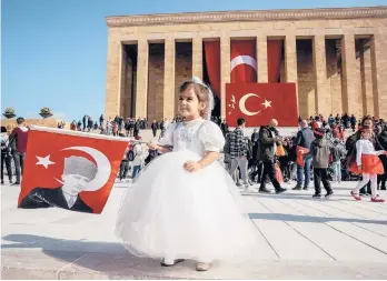  ?? ADEM ALTAN/GETTY-AFP ?? A girl poses Friday with a Turkish flag featuring a portrait of Ataturk outside Anitkabir, the mausoleum of modern Turkey’s founder Mustafa Kemal Ataturk, during the 98th Anniversar­y of the Republic ceremonies in Ankara.