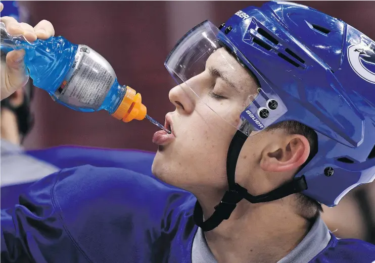  ?? RICH LAM/PNG FILES ?? Vancouver Canucks’ Troy Stecher replenishe­s his electrolyt­es during practice, something he had to do on a frequent basis during training camp.