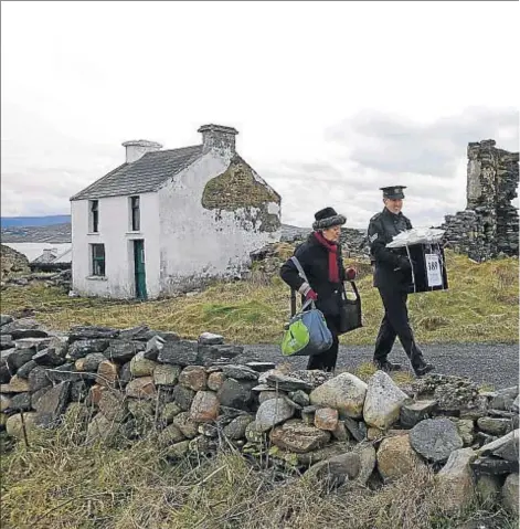  ??  ?? Una funcionari­a y un policía se llevan la urna con los votos ya depositado­s ayer en la isla de Inishbofin, que se en