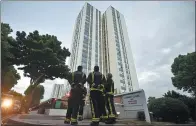  ?? HANNAH MCKAY / REUTERS ?? Firefighte­rs stand outside Burnham Tower in London, as residents were evacuated as a precaution­ary measure following concerns over the type of cladding used.