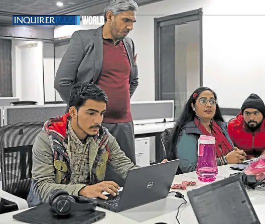  ?? —PHOTOS BY AFP ?? HELPING HAND Ibrar Bajwa (standing) founder of Taza Transformi­ng Agricultur­e visits a customer call center in Lahore on Jan. 8. Agricultur­e entreprene­urs are bringing the digital age to Pakistan’s farmers, helping them plan crops better and also distribute their produce when the time is right.