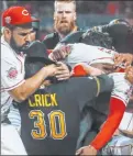  ?? John Minchillo The Associated Press ?? Reds third baseman Eugenio Suarez, left, Pirates reliever Kyle Crick and Reds reliever Amir Garrett, center, scuffle in the ninth inning of Pittsburgh’s 11-4 win Tuesday at Great American Ball Park.