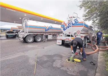  ?? CHUCK BURTON/ASSOCIATED PRESS ?? Travis Hall, right, and Brandon Deese, back, pump fuel from two tanker trucks at a convenienc­e store in Wilmington, N.C. The U.S. oil boom is shaking up old notions about the impact of higher crude prices on the U.S. economy.