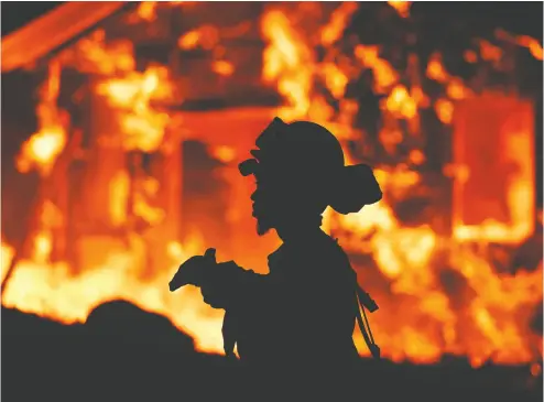  ?? JOSH EDELSON / AFP / GETTY IMAGES FILES ?? A firefighte­r monitors flames as a house burns in the Napa wine region in California. A recent New York Times headline, addressing the climate-change crisis, stated: “It Seems Odd That We Would Just Let The World Burn.”