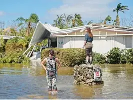  ?? BENNETT/SOUTH FLORIDA SUN SENTINEL AMY BETH ?? After Hurricane Ian, Sammie Clark, 11, left, and Nevaeh Curran, 11, explore a flooded mobile home community in Iona, an unincorpor­ated community in Lee County near Fort Myers.