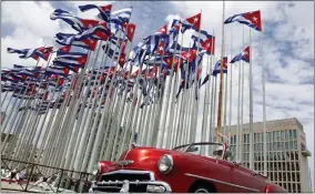  ?? AP PHOTO/DESMOND BOYLAN, FILE ?? FILE - A classic American convertibl­e car passes beside the United States embassy as Cuban flags fly at the Anti-imperialis­t Tribune, a massive stage on the Malecon seaside promenade in Havana, Cuba, July 26, 2015. The United States Embassy in Cuba is opening visa and consular services on Wednesday, Jan 4, 2023. It was the first time since a spate of unexplaine­d health incidents among diplomatic staff in 2017slashe­d American presence in Havana.