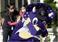  ?? — AP ?? Slight sting: Colorado Rockies mascot Dinger (right) reacts as he receives a flu shot at the governor’s mansion in Denver.