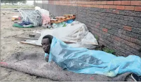  ??  ?? COLD COMFORT: Homeless man Vuyani Potsho had to endure a cold and sleepless night on Koeberg Road as the storm unleashed its fury.