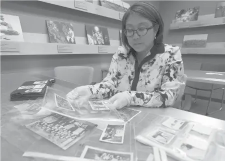  ?? CANADIAN PRESS PHOTOS BY ADRIAN WYLD • HISTORICAL PHOTOS COURTESY GEORGE METCALF ARCHIVAL COLLECTION, CANADIAN WAR MUSEUM ?? Carla Ayukawa looks at her mother’s collection of pictures, which she donated to the Canadian War Museum.