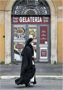  ?? Tiziana Fabi / Afp ?? Una monja pasa ante una heladería cerrada por el covid en Roma.