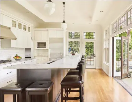  ??  ?? When the Dunlops envisioned their new kitchen, they knew they wanted classic black and white, “and a long island gathering space,” Monica said. The countertop­s are quartzite. Folding doors open to a new patio.