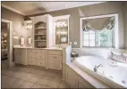  ??  ?? The master bath boasts a jetted tub, a separate shower, a two-sink vanity and a private water closet.