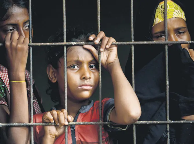  ??  ?? Rohingya from Myanmar look through a fence at the immigratio­n detention center in Lhokseumaw­e, in Indonesia’s North Aceh Regency, June 26, 2020.