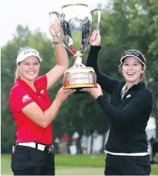 ?? VAUGHN RIDLEY/GETTY IMAGES ?? Henderson and her sister Brittany, also her caddie, hoist the trophy after she finished at 21 under.