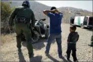  ?? JAE C. HONG — THE ASSOCIATED PRESS FILE ?? In this file photo, a Guatemalan father and son, who crossed the U.S.-Mexico border illegally, are apprehende­d by a U.S. Border Patrol agent in San Diego. California will introduce group trials on Monday, July 9, for people charged with entering the...