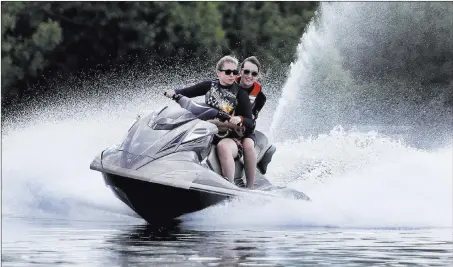  ?? Michael Probst ?? Two Russian girls enjoy a personal watercraft ride on a small lake Thursday in Vatutinki near Moscow. The Associated Press