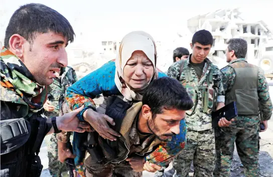  ??  ?? Fighters of Syrian Democratic Forces evacuate a civilian from the stadium after Raqqa was liberated from Daesh in on Tuesday. (Reuters)