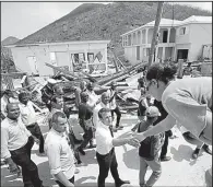  ?? AP/CHRISTOPHE ENA ?? French President Emmanuel Macron (center) greets residents Tuesday during a tour of the storm-ravaged island of St. Martin. He pledged a fast recovery for the island.