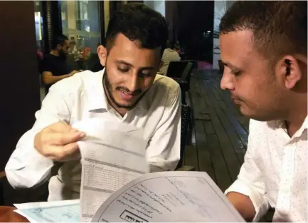  ?? (Rozanna Latiff/Reuters) ?? RAFEK AHMED Mohammed Al-Sanani (right), 22, and Abdel Rahman Zaid, 26, look through documents as they speak with Reuters in Serdang, on the outskirts of Kuala Lumpur, Malaysia, last week.