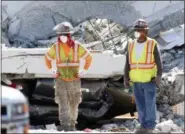  ?? THE ASSOCIATED PRESS ?? Workers stand in front of crushed cars under a section of a collapsed pedestrian bridge Friday near Florida Internatio­nal University.