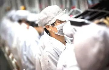  ??  ?? Employees of Hon Hai Precision Industry Co. work on a production line in the Longhua Science and Technology Park, also known as Foxconn City, in Shenzhen, China, on Sept 4, 2010. — WP-Bloomberg photos