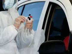  ??  ?? A healthcare worker conducting a coronaviru­s test at a drive-through testing centre for NHS