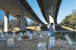  ??  ?? Volunteer Sarah Batt, 12, carries a bucket of white paint at the pet cemetery, which resides beneath the viaduct to the Golden Gate Bridge.