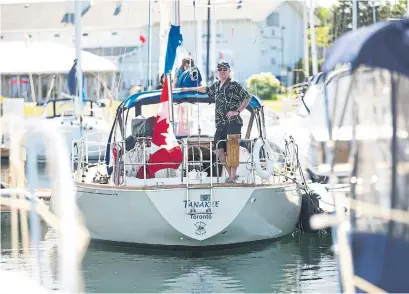  ?? LUCAS OLENIUK PHOTOS/TORONTO STAR ?? Rick Marshall on the stern of his family’s sailboat and home Tanakee, with son William up top, in Port Credit Yacht Club.