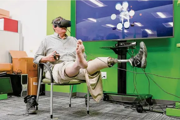  ?? Photos by Shafkat Anowar/Dallas Morning News ?? Retired Navy veteran Dean Peterson wears a virtual reality headset as he demonstrat­es a new therapy, called Mr. MAPP, that creates a virtual image of a person’s missing limb to trick the brain. An estimated 80 percent of amputees experience some form of phantom limb pain, according to the Cleveland Clinic.