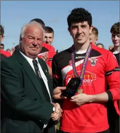  ??  ?? Pat Fortuneof the Wexford League presenting the man of the match trophy to Jack Burford of St. Leonards.