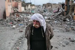  ?? JOHN MOORE/GETTY IMAGES FILES ?? A man walks through the rubble of his neighbourh­ood on Nov. 15 in Sinjar, Iraq, after Kurdish forces, aided by U.S.-led coalition airstrikes, liberated the town from extremists.