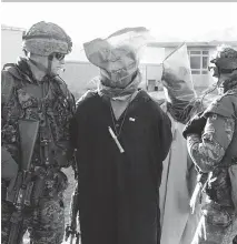  ??  ?? Canadian soldiers escort detainees in Afghanista­n in 2004. The defence department’s new acquisitio­n guide lists a deployable holding facility.