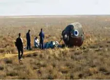  ?? (REUTERS) ?? Des experts dans la steppe kazakhe autour de la cabine Soyouz revenue en catastroph­e des confins de l’espace.