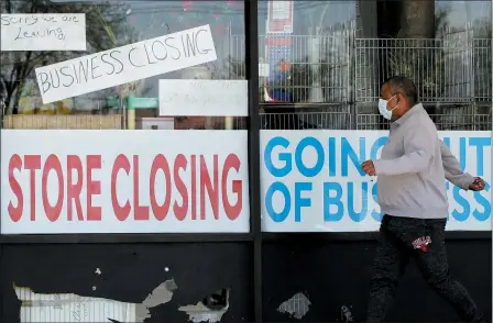  ?? THE ASSOCIATED PRESS ?? A man looks at signs of a closed store due to COVID-19in Niles, Ill., May 21. More than 2.4million people applied for U.S. unemployme­nt benefits last week in the latest wave of layoffs from the viral outbreak that triggered widespread business shutdowns two months ago and sent to economy into a deep recession.