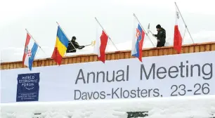  ?? — Reuters ?? Workers shovel snow from the roof of the congress centre, the venue of the upcoming World Economic Forum in the Swiss mountain resort of Davos.