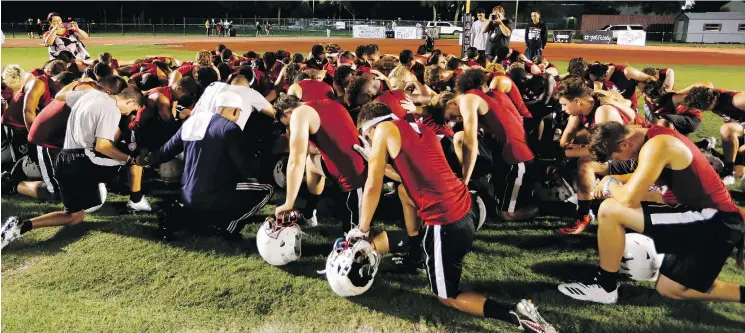  ?? — THE ASSOCIATED PRESS ?? Members of the Marjory Stoneman Douglas High School football team pray together as they began practice just after midnight on Monday in Parkland, Fla.
