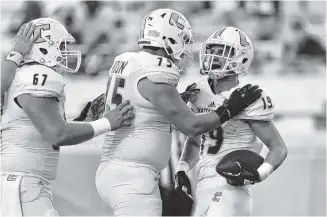  ?? CONTRIBUTE­D PHOTOS BY CLIFF LAVELLE/UTC ATHLETICS ?? UTC wide reciever Bryce Nunnelly, right, celebrates with teammates after scoring a touchdown against The Citadel on Saturday in Charleston, S.C. Nunnelly had two recieving touchdowns and passed to Jordan Giberti for the winning two-point conversion in overtime.