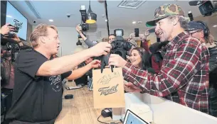  ?? PAUL DALY THE CANADIAN PRESS ?? Canopy Growth CEO Bruce Linton, left, passes a bag with the first legal cannabis for recreation use sold in Canada to Nikki Rose and Ian Power at the Tweed shop in St. John's, N.L.