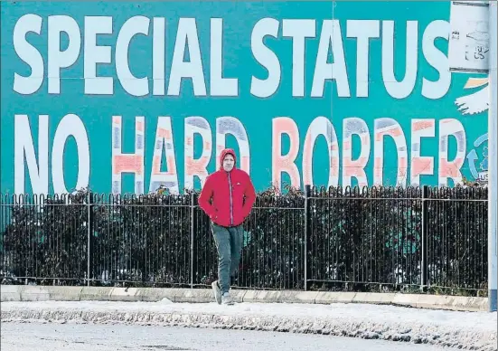  ?? PAUL FAITH / AFP ?? Un home passa davant d’un cartell reclamant un estatus especial per a la frontera amb Irlanda a Belfast