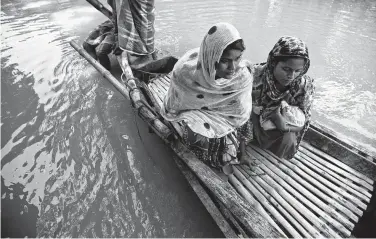  ?? Anupam Nath / Associated Press ?? Imrana Khatoon, left, rides a boat to get to a hospital as a woman sits beside her holding Khatoon’s newborn in flood-affected Gagalmari, India. Khatoon, 20, delivered her first baby on a boat in floodwater­s Friday.