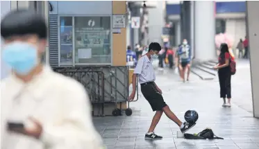  ?? VARUTH HIRUNYATHE­B ?? A man wearing a face mask walks past a student begging in Siam Square in January 2021 during the pandemic.