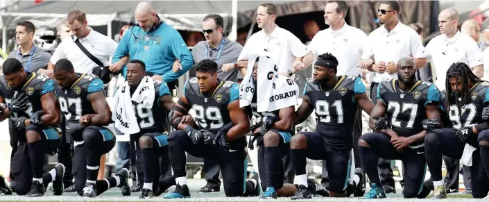  ??  ?? Solidarity: Jacksonvil­le Jaguars players kneel and link arms for the American national anthem before an NFL game at Wembley Stadium in London yesterday